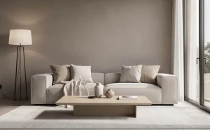 Salon minimaliste aux tons greige avec mobilier beige-gris et lumière naturelle diffuse entrant par de grandes fenêtres.