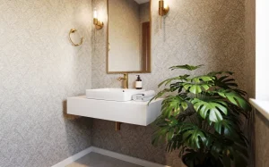 Petite salle de bains élégante avec papier peint à motifs, détails en laiton, plante verte et lavabo minimaliste.