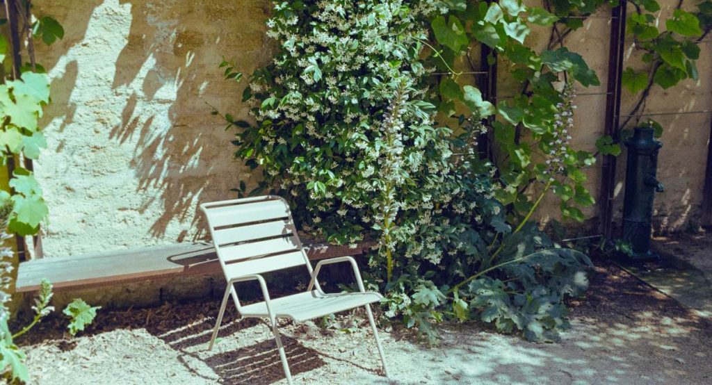 Petit coin de jardin cosy avec une chaise contre un mur fleuri
