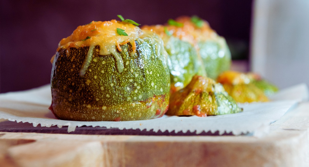 Courgettes rondes farcies et gratinées au fromage sur une planche