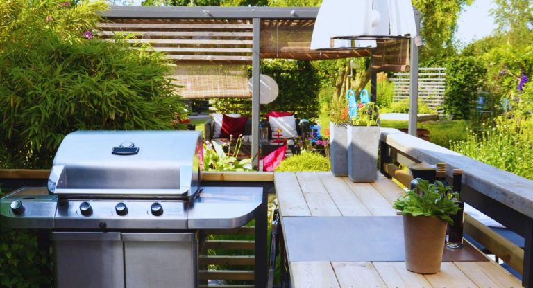 Cuisine extérieure aménagée avec barbecue au gaz et espace repas en bois