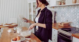 Femme consultant un livre de recettes en preparant une pate en cuisine
