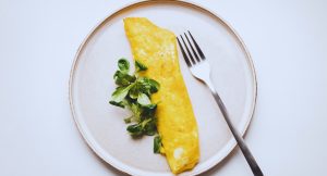 Omelette pliee accompagnee de jeunes pousses vertes sur assiette