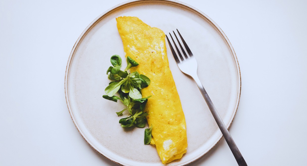 Omelette pliee accompagnee de jeunes pousses vertes sur assiette